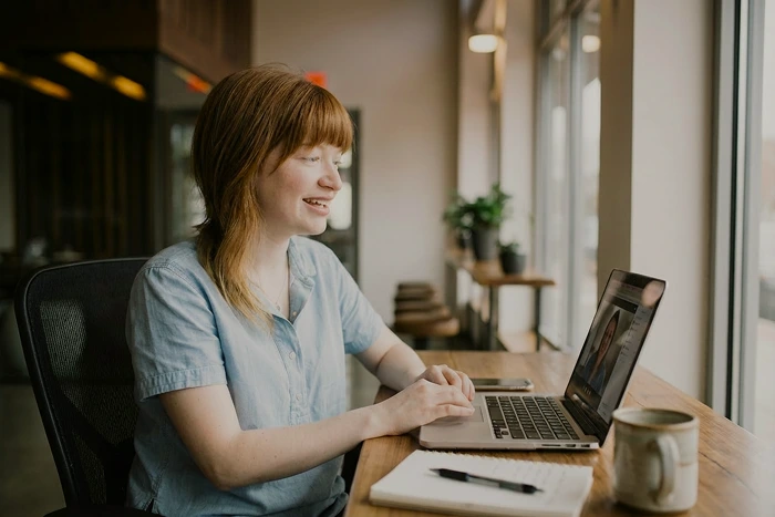 En AI-modifierad bild på en person sitter vid ett skrivbord och har ett videomöte på sin laptop